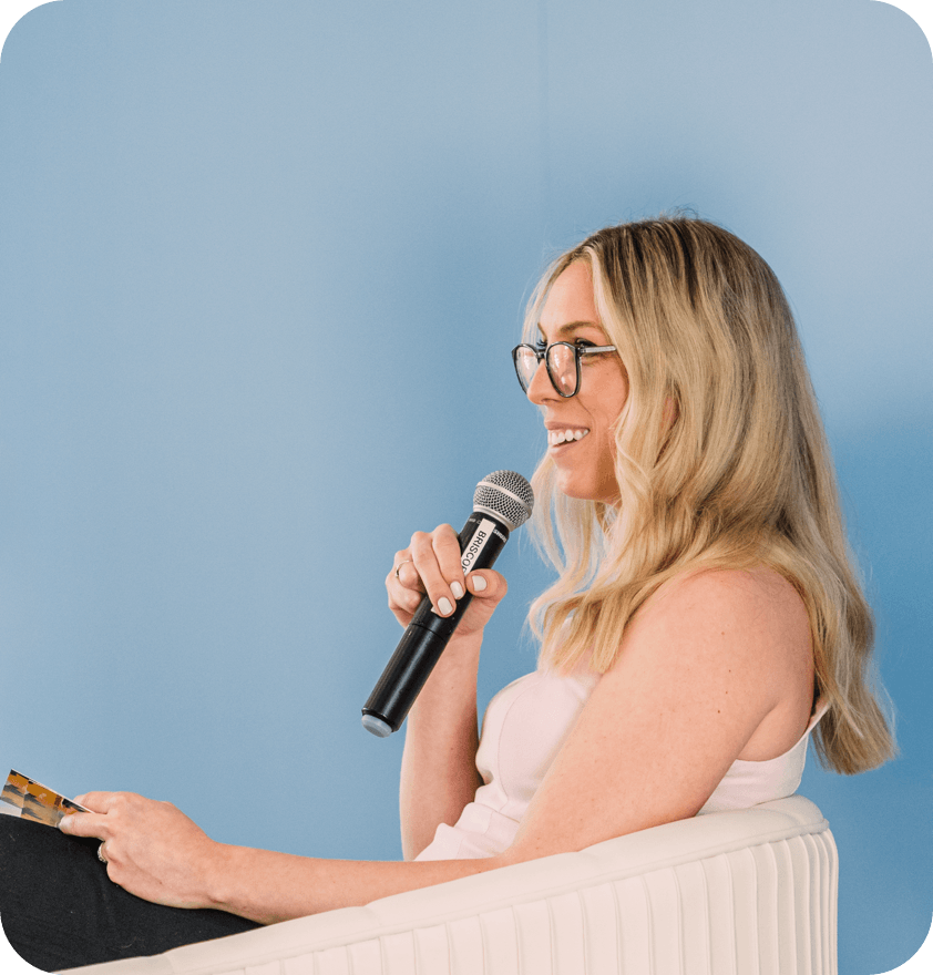 Jess VanderWier speaking into a microphone at an event.